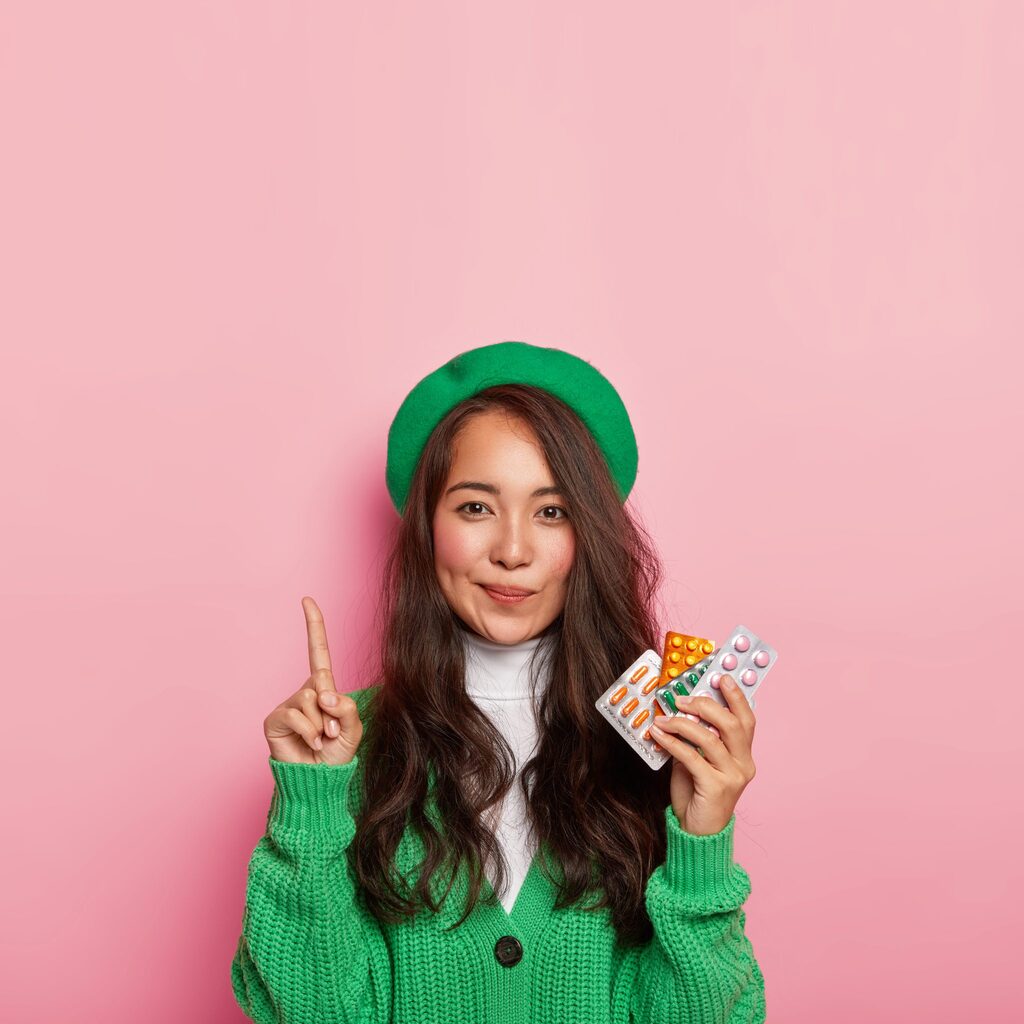 adorable-woman-points-holds-painkillers-has-problems-with-health-shows-way-chemists-shop-dressed-green-fashionable-outfit-2048x2048